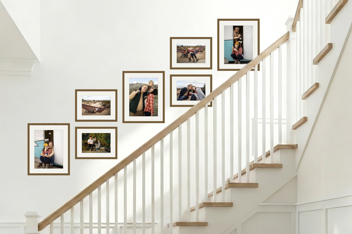 A staircase family photo wall: 7 frames climbing the stair diagonal, seen on every trip up and down